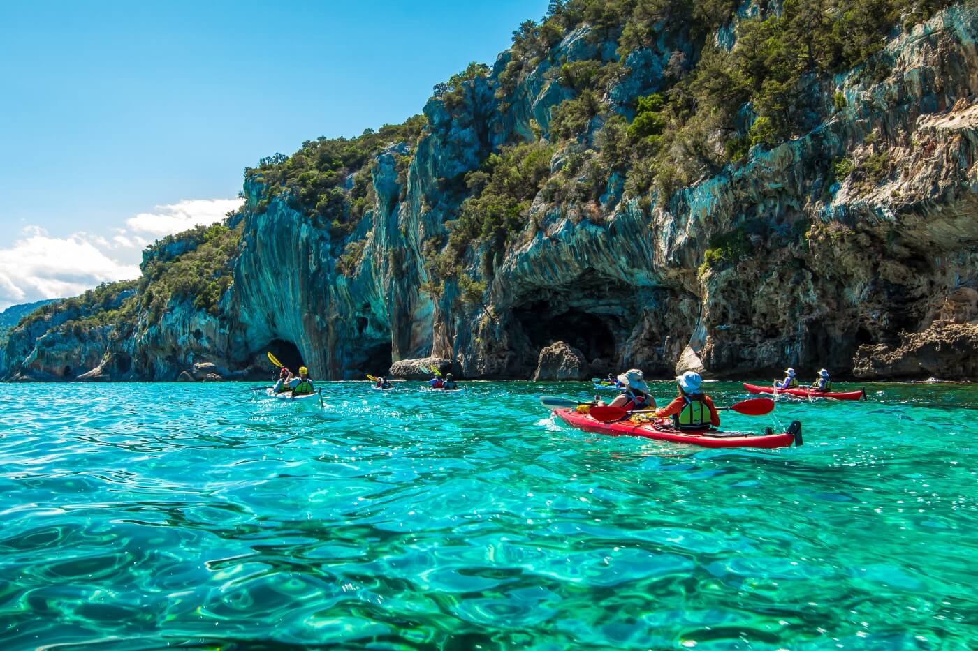 Groupe de kayakistes pagayant entre falaises marines
